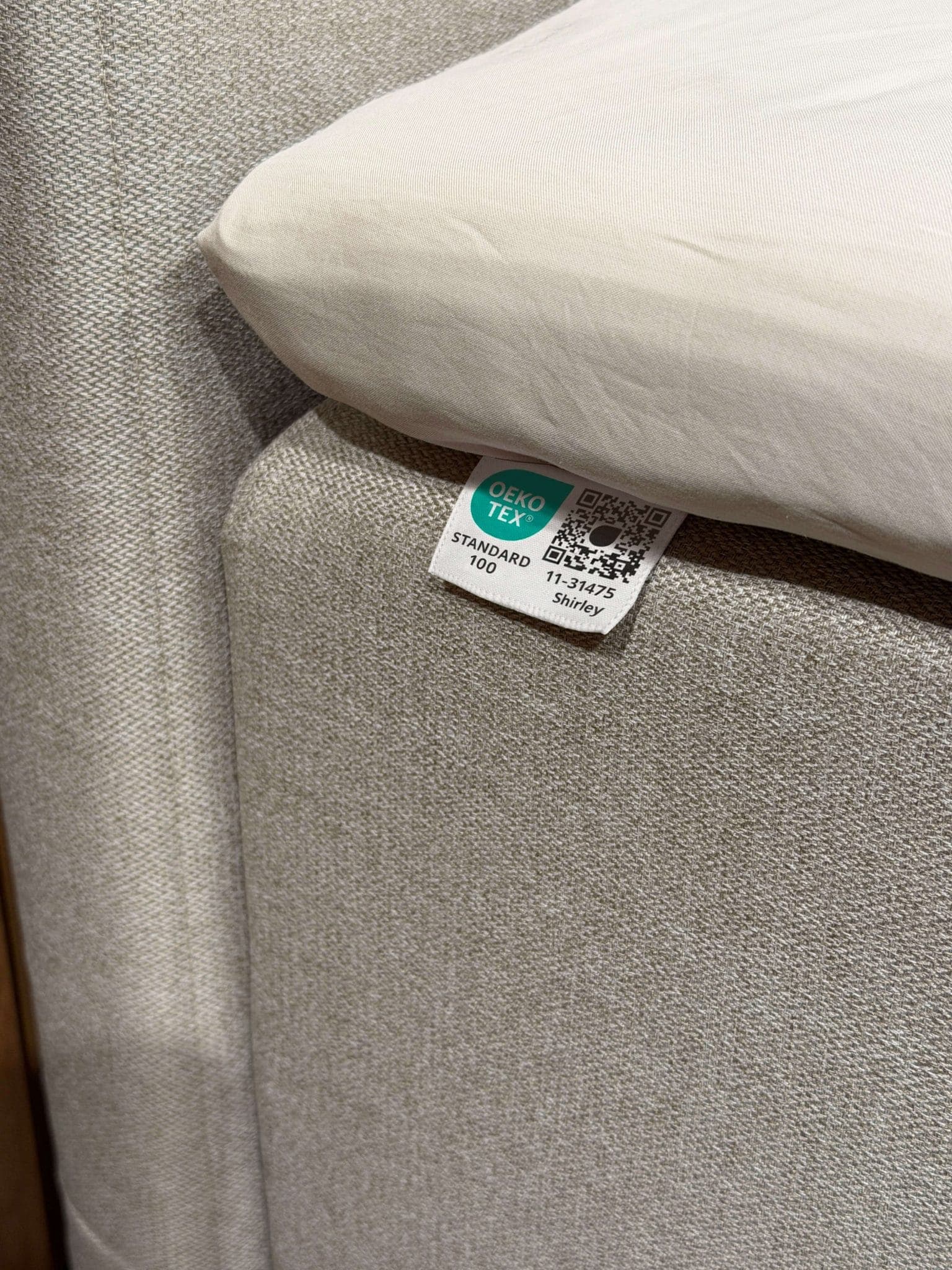 OEKO-TEX® STANDARD 100-märkning fastsydd i sängens beige tyg under lakanet
