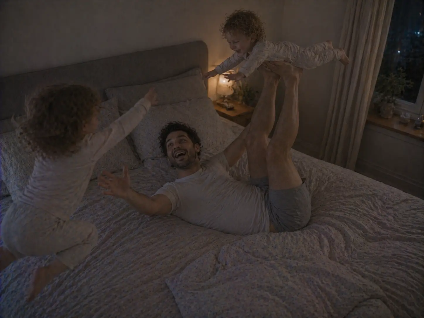 En pappa leker flygplan med det ena barnet i sängen medan det andra hoppar bredvid