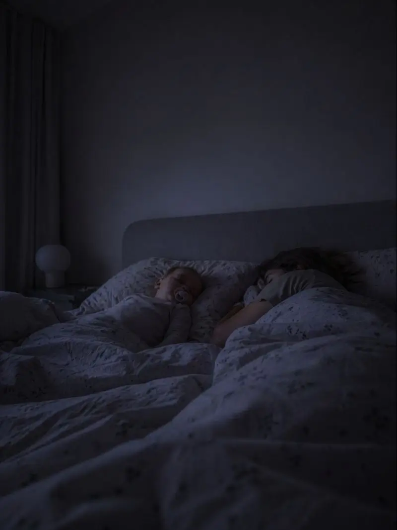 Föräldrar och ett barn sover tätt tillsammans i sängen i dämpat nattljus