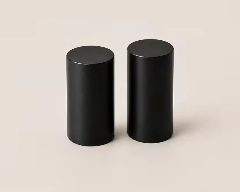 Två svarta cylindriska mittben på en ljus yta